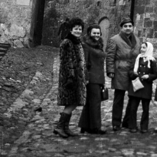 Family poses in front of a stone archway and wall.