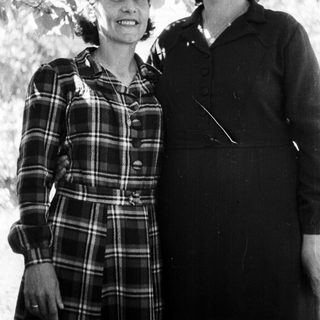 Here's a brief summary of the image: Two women stand together outdoors, posing for a portrait.