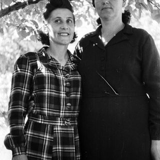 Here's a brief summary of the image: Two women stand together outdoors, posing for a portrait.