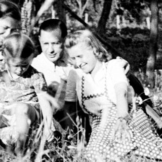 Family portrait outdoors in tall grass, vintage photograph.