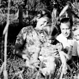 Family portrait outdoors in tall grass, vintage photograph.