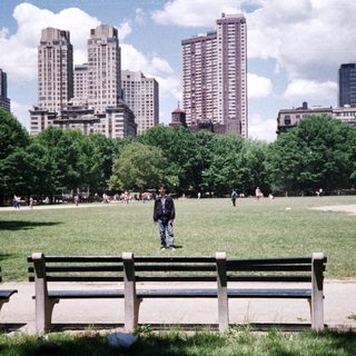 People relax in a park with city buildings in background.
