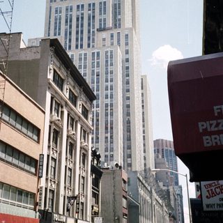 Here's a brief summary of the image: New York City street scene with a tall building in background.