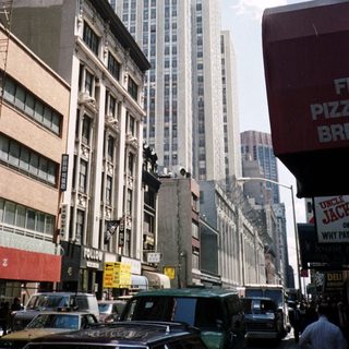 Here's a brief summary of the image: New York City street scene with a tall building in background.