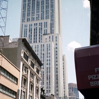 Here's a brief summary of the image: New York City street scene with a tall building in background.