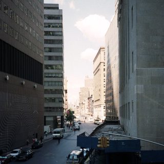 Here's a brief summary of the image: Urban street scene with tall buildings and traffic.