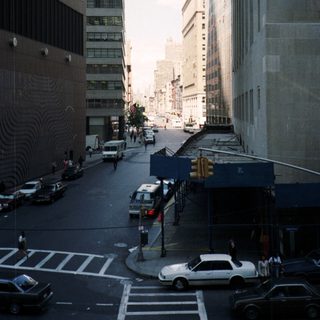 Here's a brief summary of the image: Urban street scene with tall buildings and traffic.