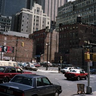 Here's a brief summary of the image: New York City street scene with buildings and cars.