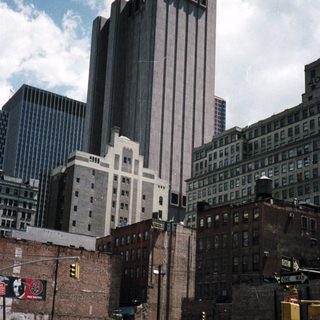 Here's a brief summary of the image: New York City street scene with buildings and cars.