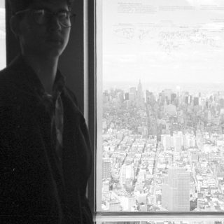 Person looking out a window with a city skyline view.