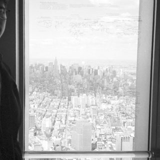 Person looking out a window with a city skyline view.