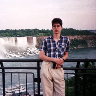 Man stands near Niagara Falls, taking a photo.