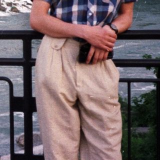 Man stands near Niagara Falls, taking a photo.