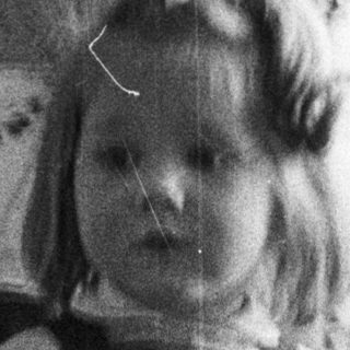 Here's a brief summary of the image: Black and white photo of a young girl in a dress.