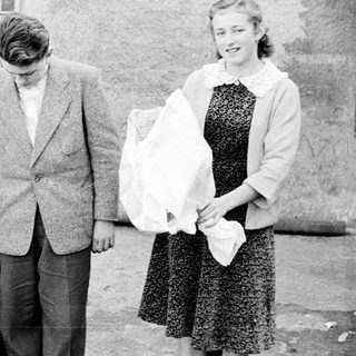 Three people and a dog stand outside a building.