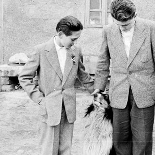 Three people and a dog stand outside a building.