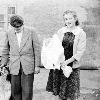 Three people and a dog stand outside a building.