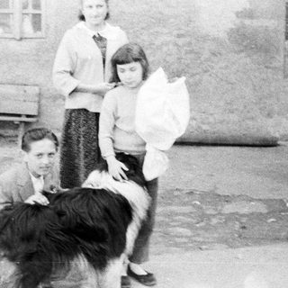 Three people and a dog stand outside a building.