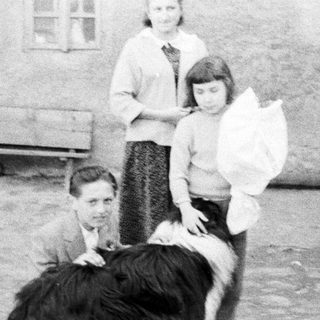 Three people and a dog stand outside a building.