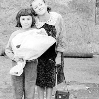 Two girls holding a baby outdoors with a dog.