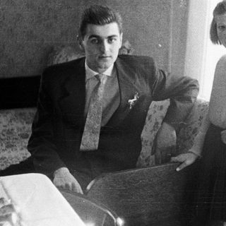 Man and young girl posing indoors in a bedroom.