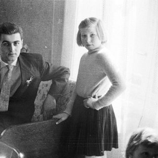 Man and young girl posing indoors in a bedroom.
