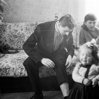 Man interacts with children in a vintage living room.