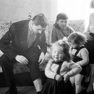 Man interacts with children in a vintage living room.
