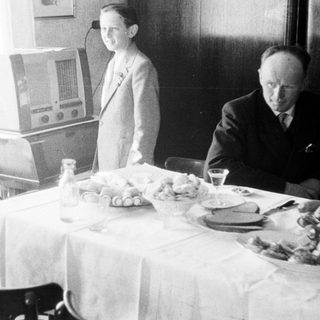 Man and boy at table with food and radio.