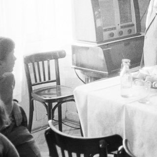 Man and boy at table with food and radio.