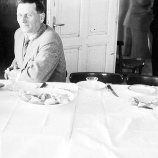 Man seated at a table with food and tableware.