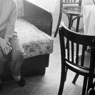Girl sits on floral sofa in a vintage room.
