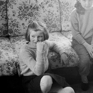 Girl sits on floral sofa in a vintage room.