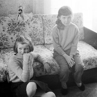Girl sits on floral sofa in a vintage room.