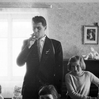 Man smoking in a room, two girls nearby.