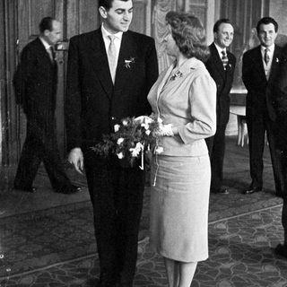 Couple poses with attendants in a formal setting.