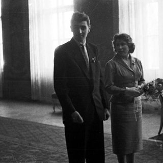 Couple stands in room, likely after a wedding.