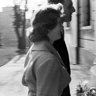 Couple walks outdoors, likely during a wedding or formal event.