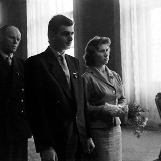 Couple standing with a man in a formal setting.