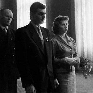 Couple standing with a man in a formal setting.