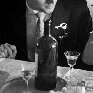 Couple seated at a table with food and drinks.