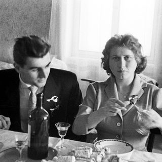 Couple seated at a table with food and drinks.