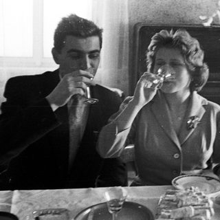 Couple drinks wine at a table with food.