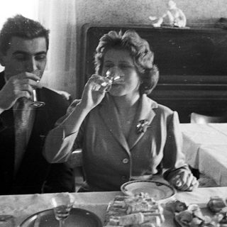 Couple drinks wine at a table with food.