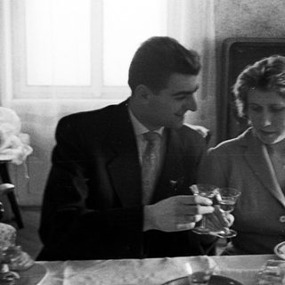 Couple seated at a table, holding drinks indoors.