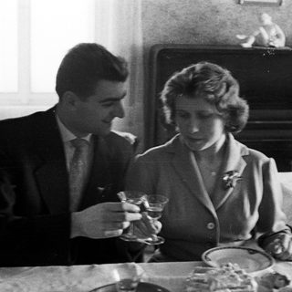 Couple seated at a table, holding drinks indoors.