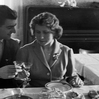 Couple seated at a table, holding drinks indoors.