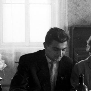 Here's a brief summary of the image: Black and white photo of a couple seated at a table.