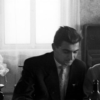 Here's a brief summary of the image: Black and white photo of a couple seated at a table.