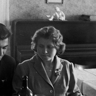 Here's a brief summary of the image: Black and white photo of a couple seated at a table.